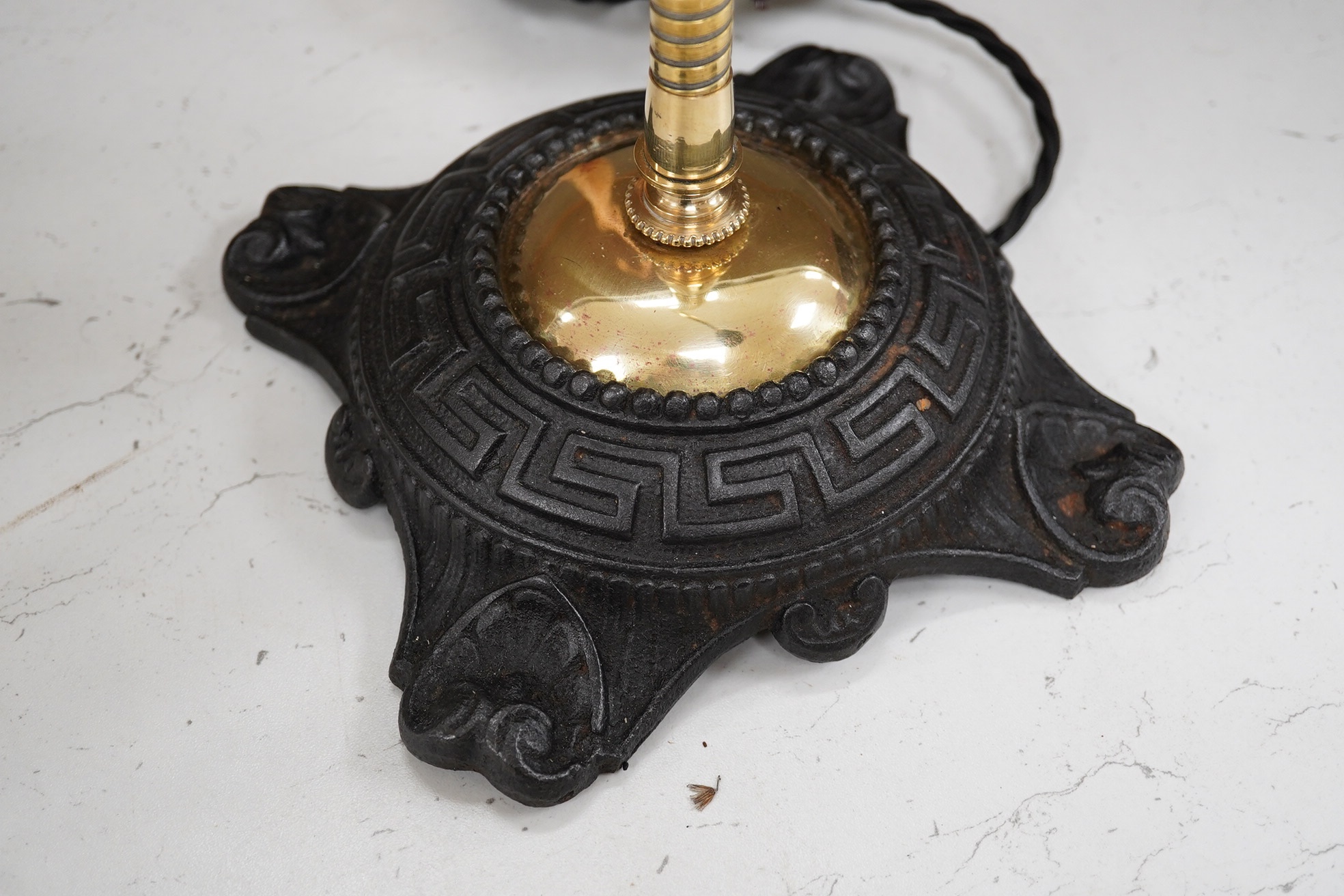 An English desk lamp wrought iron base with flexy brass arm and brass shell shape shade, early 20th century, wired, 55cm high, base 17cm diameter. Condition - good